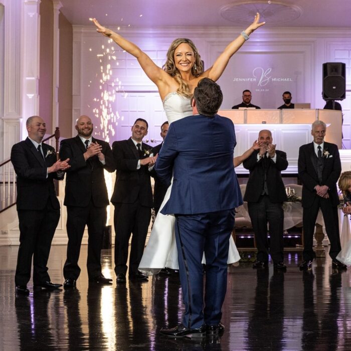 groom lifting a bride into the air while celebrating